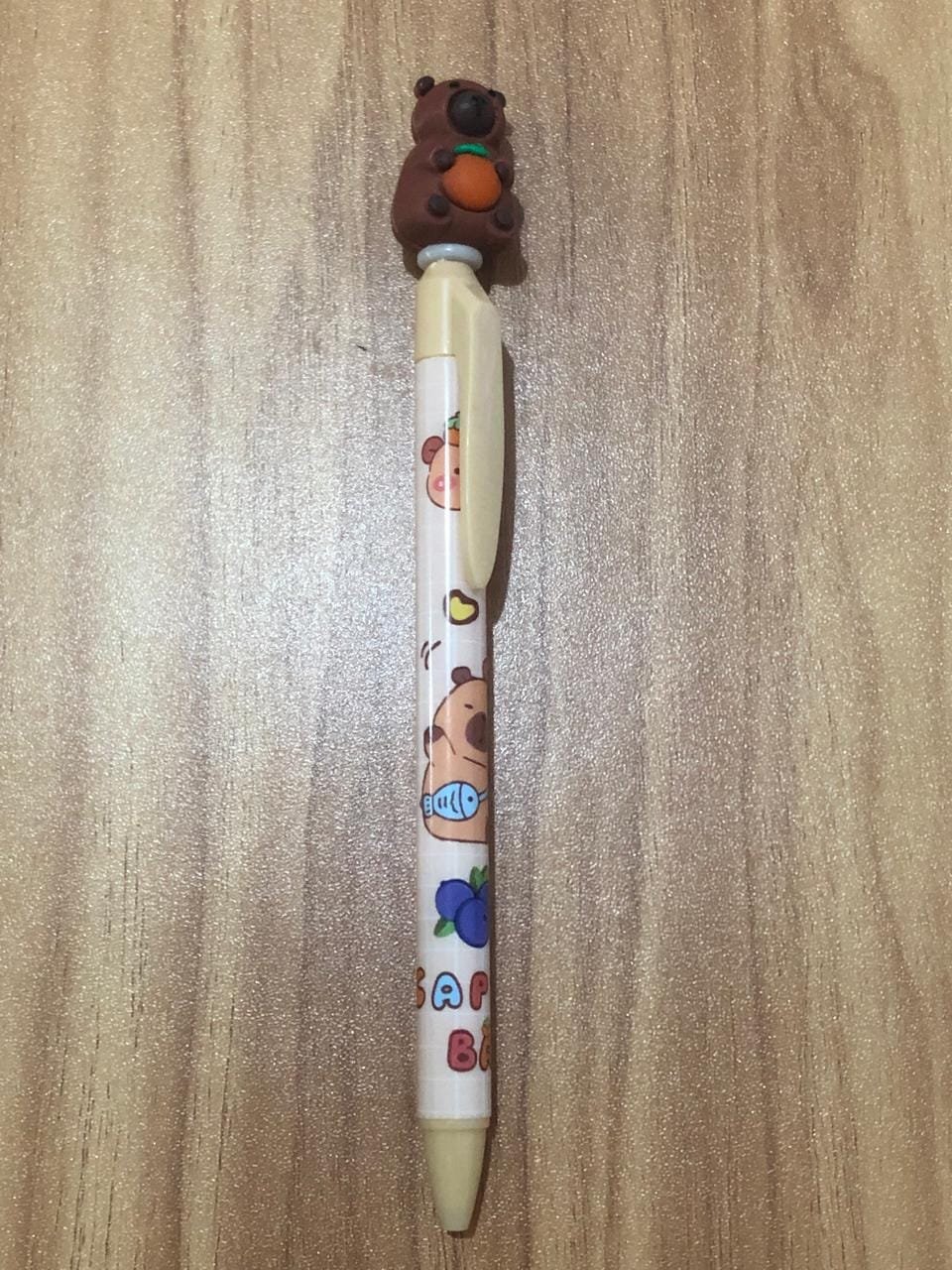 Caneta Bege com Capivara na ponta Segurando uma Fruta